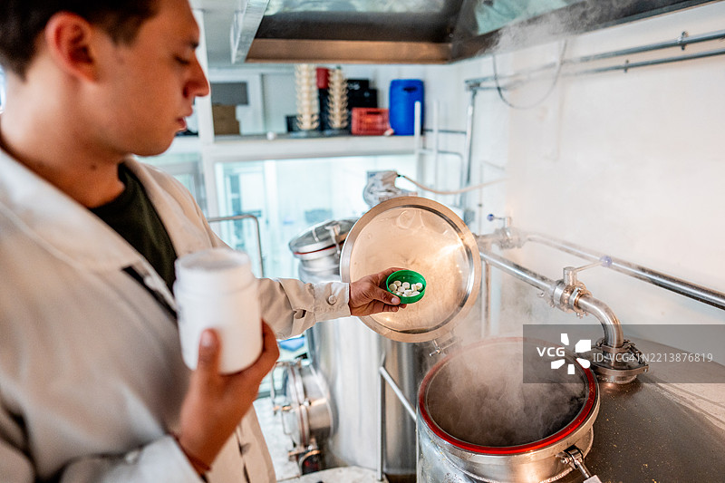 员工在酿酒厂的酿造罐中添加原料的特写镜头图片素材