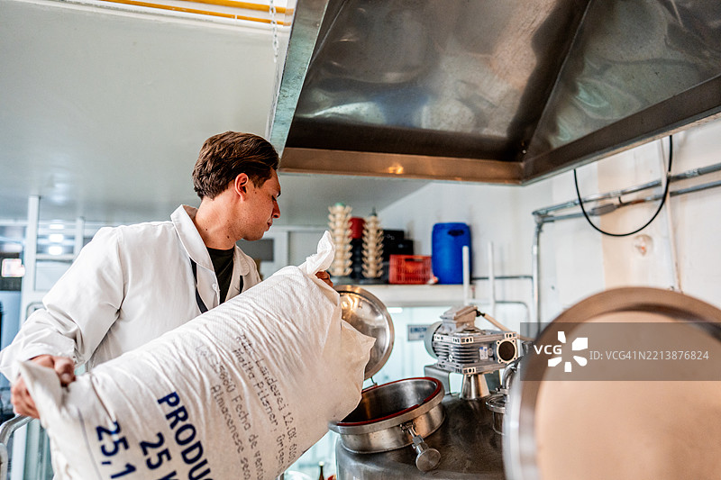 员工在酿酒厂的酿造罐中添加原料图片素材