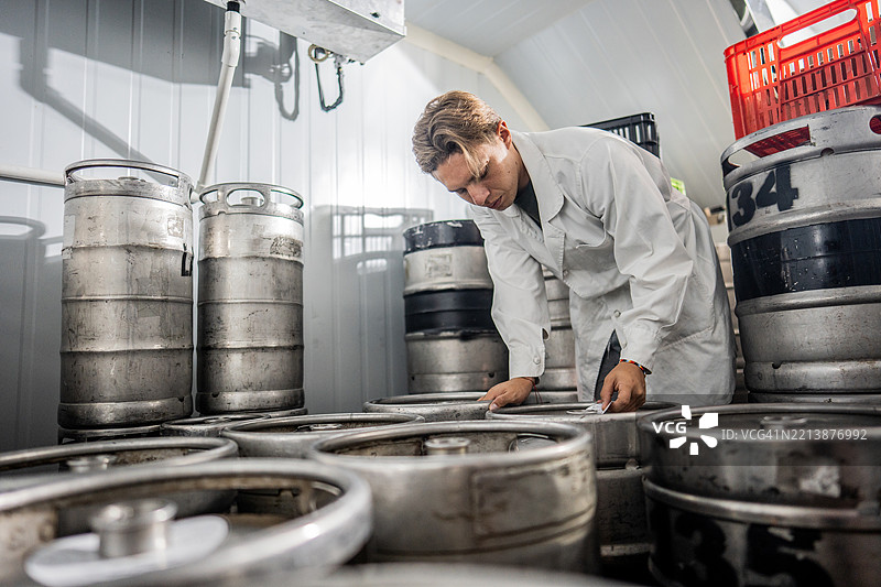 员工在酿酒厂的冷藏室检查啤酒桶图片素材