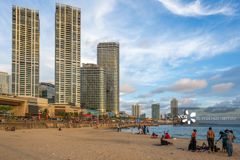在斯里兰卡科伦坡，海滩上的人们与背景中的摩天大楼。图片素材