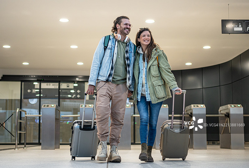 快乐的游客夫妇在火车站提着行李走着图片素材