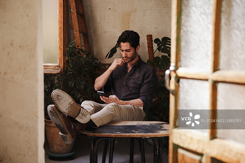 一位留着三天胡须的帅气男士坐着望向窗外图片素材
