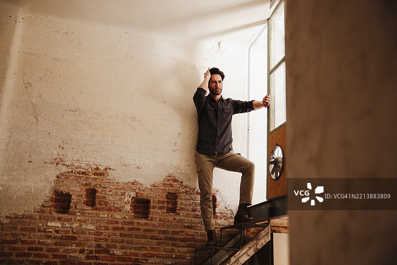 一个留着三天胡须的帅气男人站在窗边图片素材