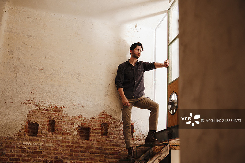 一个留着三天胡须的帅气男人站在窗边图片素材