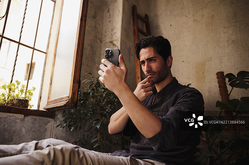 一位留着三天胡须的帅气男士用手机自拍图片素材