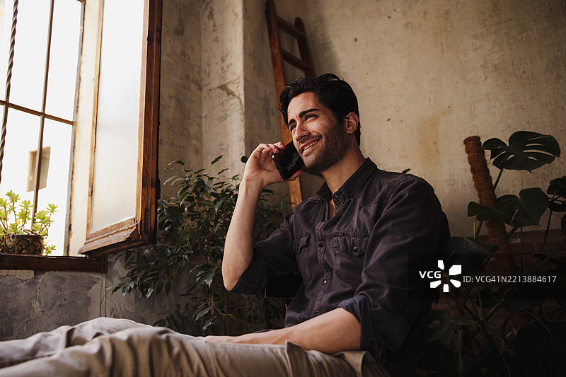 一位留着三天胡须的帅气男士正在用手机通话图片素材