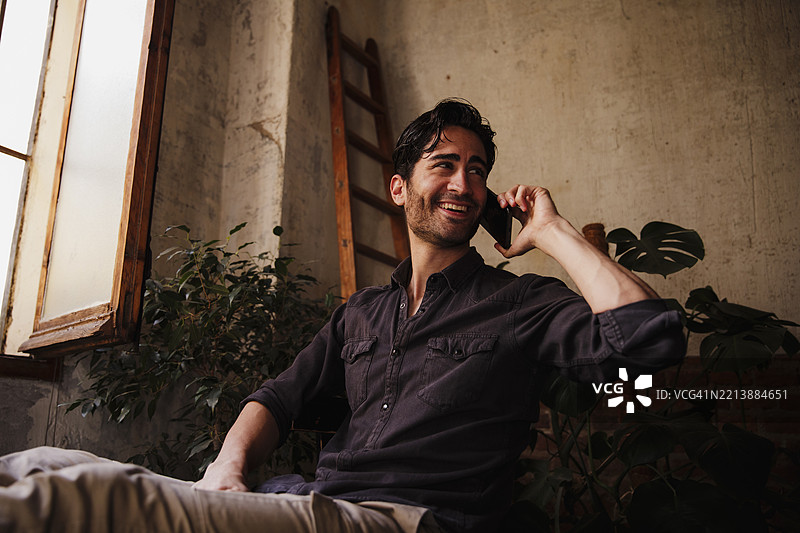 一位留着三天胡须的帅气男士正在用手机通话图片素材