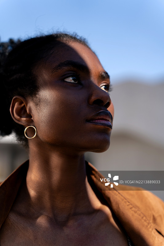 户外站着的年轻黑人女性特写肖像，脸上有阴影图片素材