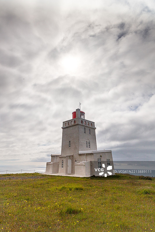 迪尔霍拉伊灯塔位于南冰岛迪尔霍拉伊海滩的悬崖上，阴天。图片素材