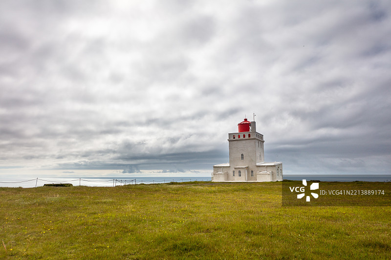 迪尔霍拉伊灯塔位于南冰岛迪尔霍拉伊海滩的悬崖上，阴天。图片素材
