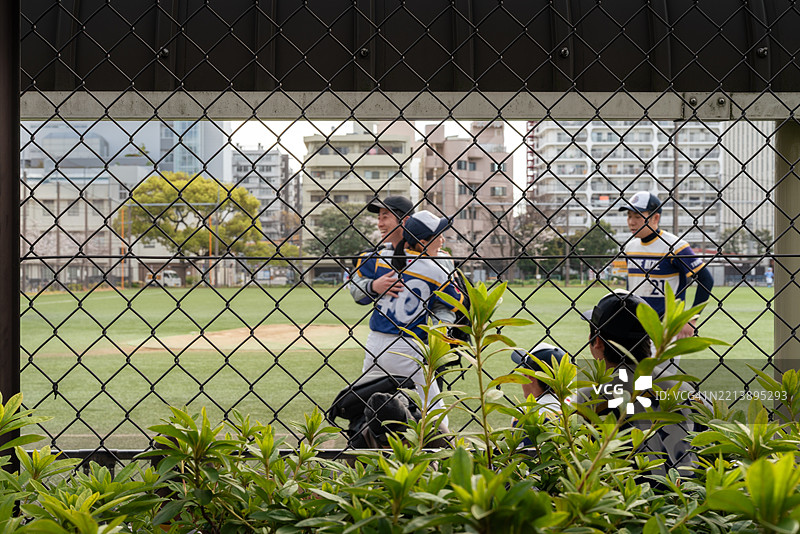 当地棒球队在城市球场的铁丝网围栏旁训练图片素材