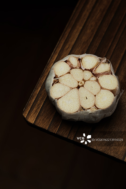 黑色背景下切菜板上的大蒜俯视图图片素材