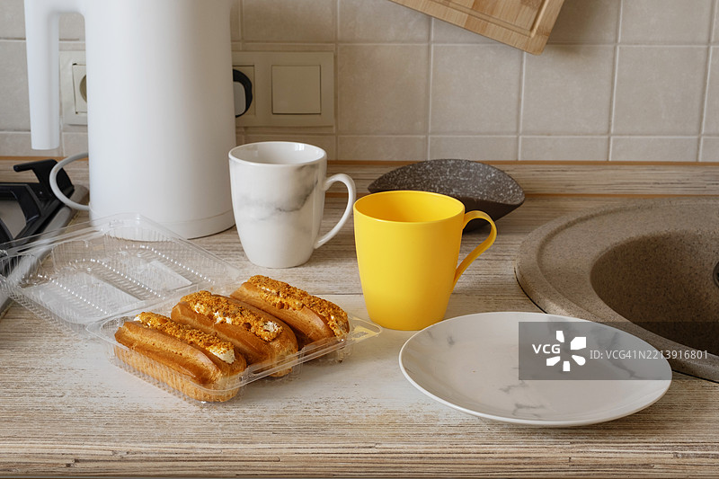 早晨例行活动中，厨房台面上摆放着烘焙食品、杯子和盘子。图片素材