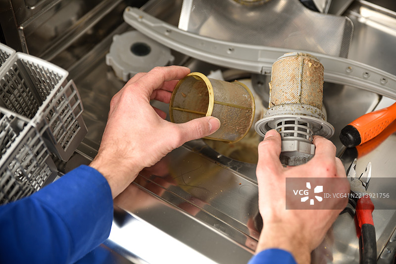 技术人员的手在进行洗碗机维护的细节图片素材