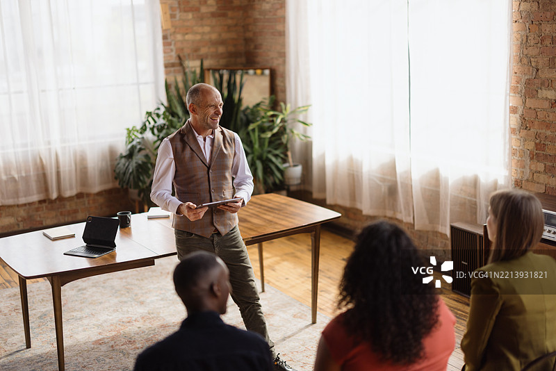 成熟的商人正在用平板电脑带领团队开会图片素材