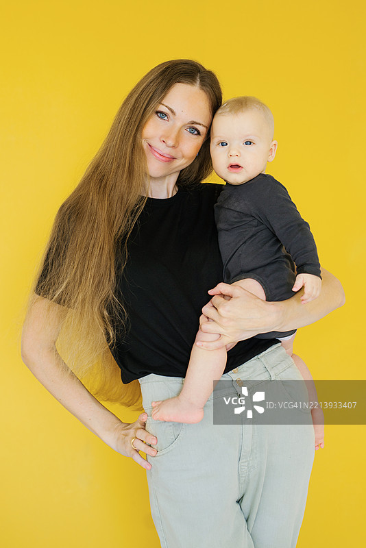年轻女性怀抱着男婴，母亲与孩子之间温暖而充满爱的时刻图片素材