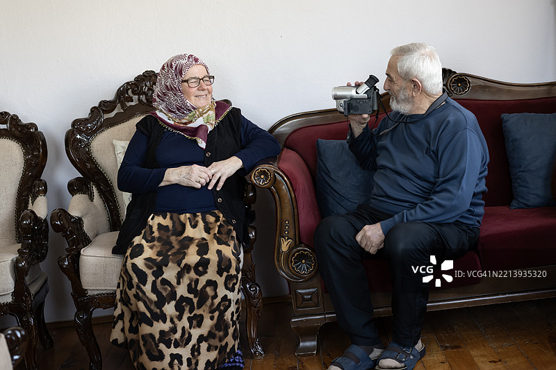 老年男子在客厅用老式摄像机录制视频图片素材