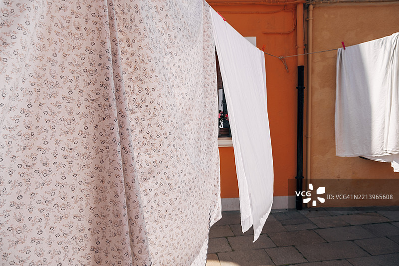 床单在户外阳光和微风中晾干。图片素材