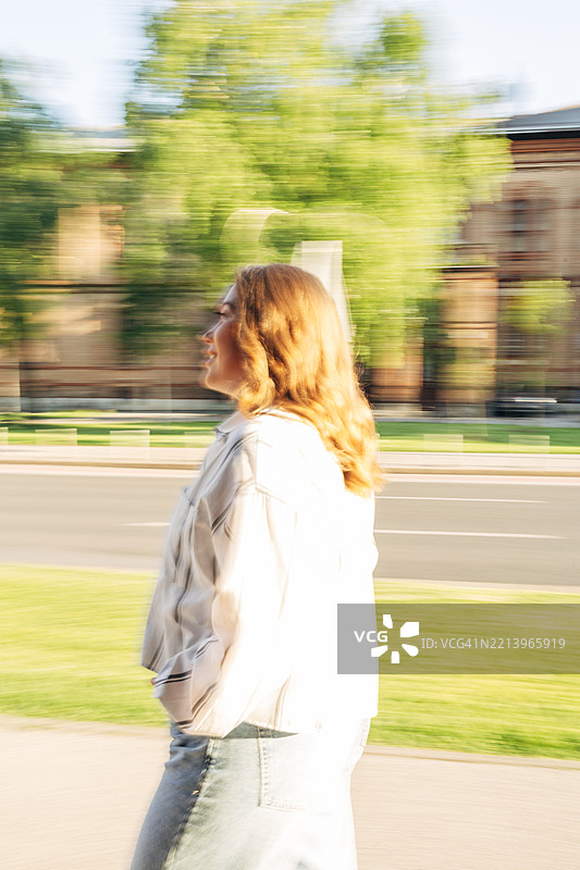 模糊的照片中，一位女性在城市中行走，展现出动态感。图片素材