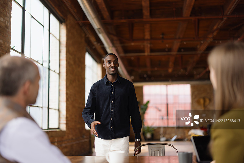 年轻的商人在现代办公室里带领同事们开会图片素材