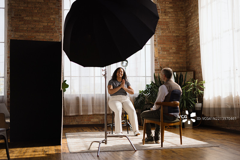 摄影师在阁楼工作室为微笑的模特拍照图片素材