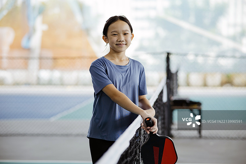 微笑的女孩在进行乒乓球练习时手持球拍图片素材