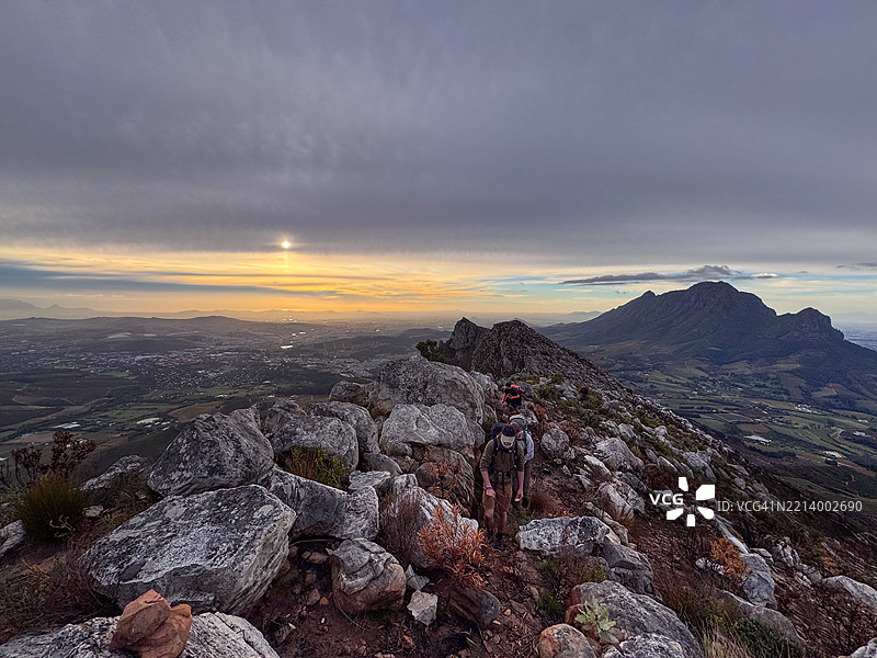 一群徒步旅行者在壮丽的日落时分穿越风景如画的山间小径图片素材