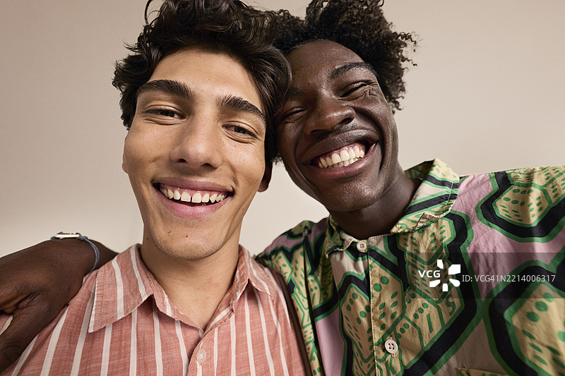 男性朋友在米色背景下欢笑图片素材