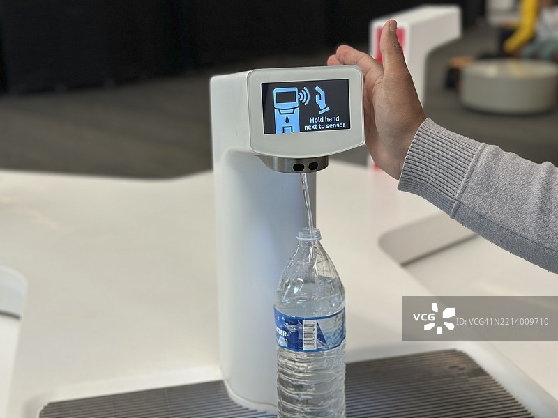 男子在机场航站楼的自动加水站用手感应器加水图片素材