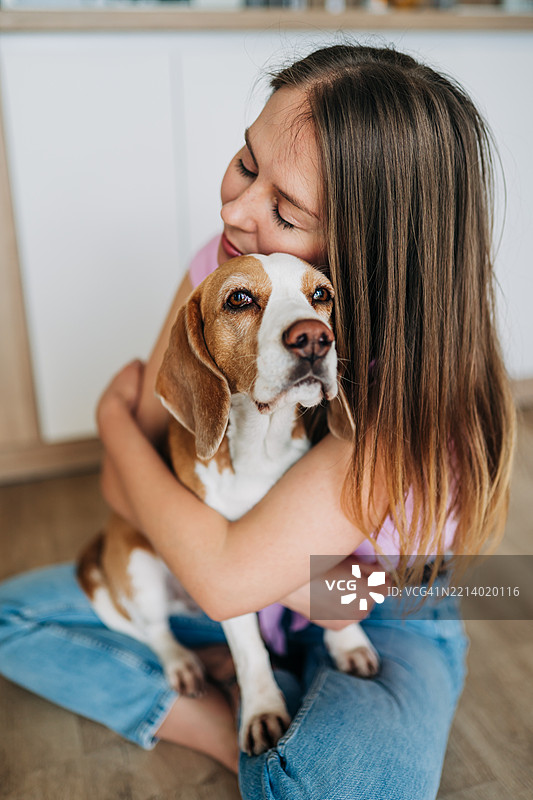 女人在温暖而充满爱的场景中拥抱一只比格犬图片素材