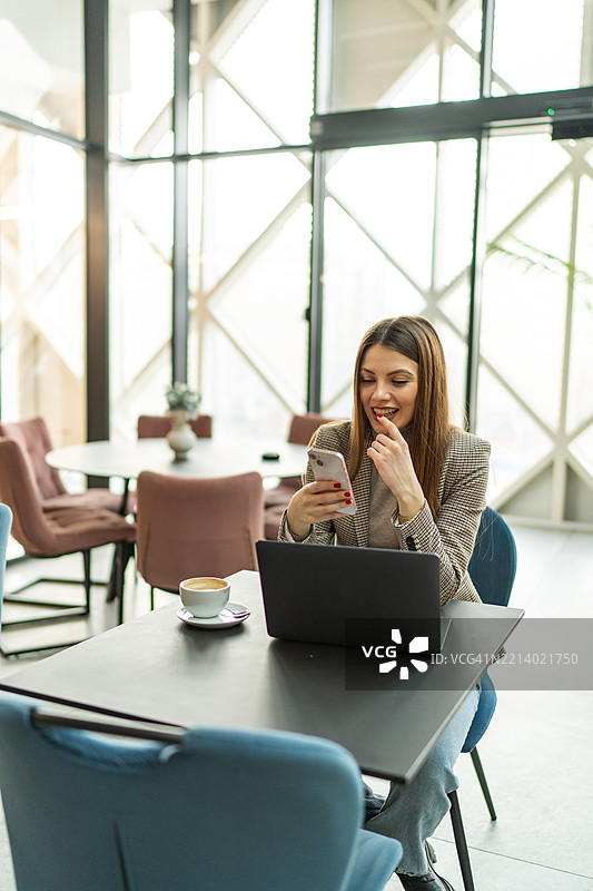 女商人在咖啡馆使用智能手机和笔记本电脑图片素材