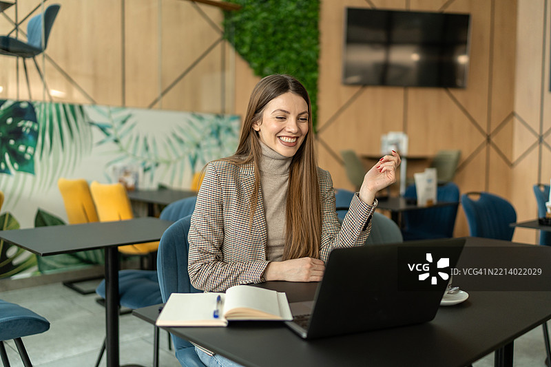 年轻女商人在咖啡馆微笑着使用笔记本电脑工作图片素材