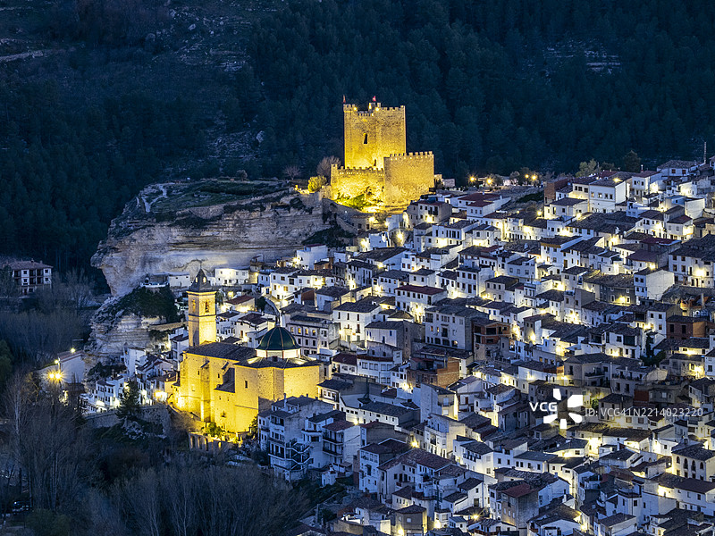 小镇的房屋，配有城堡和教堂，街灯亮起。阿尔卡拉德胡卡村。图片素材