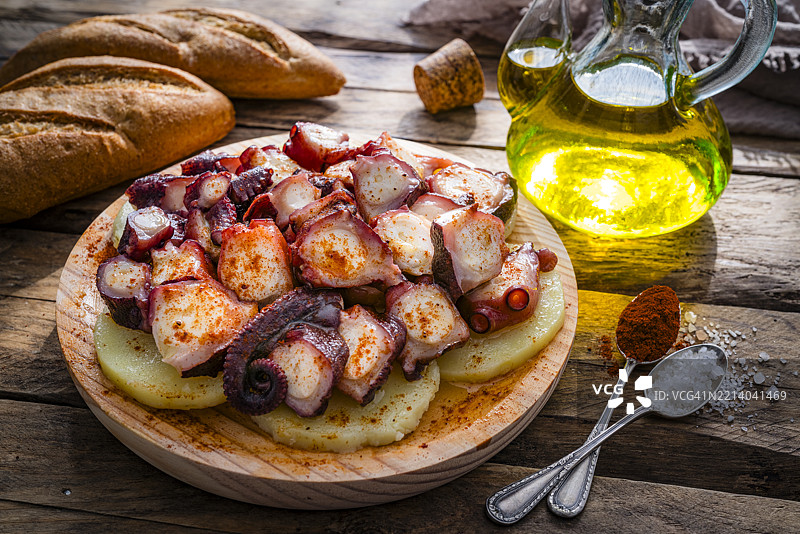 西班牙美食：加利西亚风味章鱼。章鱼触手和煮土豆，撒上红椒粉，放在木托盘上。图片素材