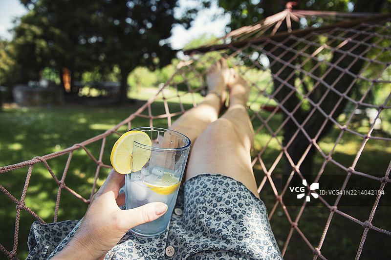 女人在吊床上休息，手里拿着柠檬水图片素材