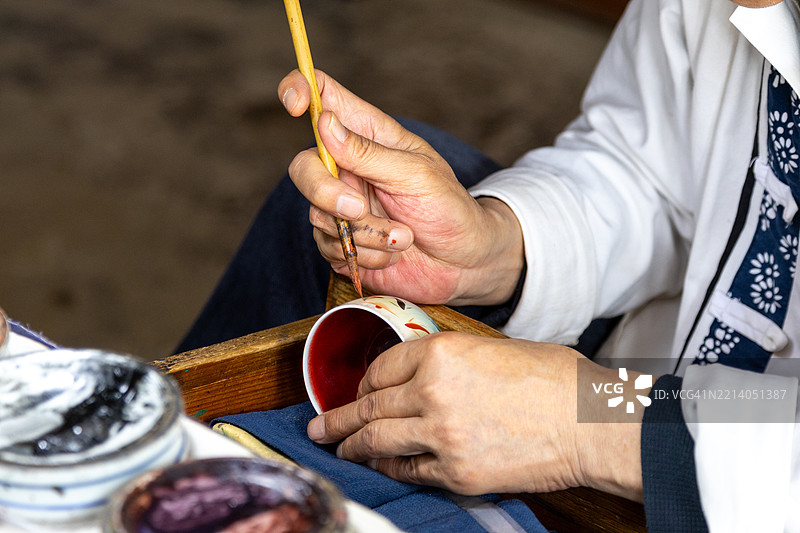 工人在中国景德镇的一家陶瓷工厂装饰瓷杯。图片素材