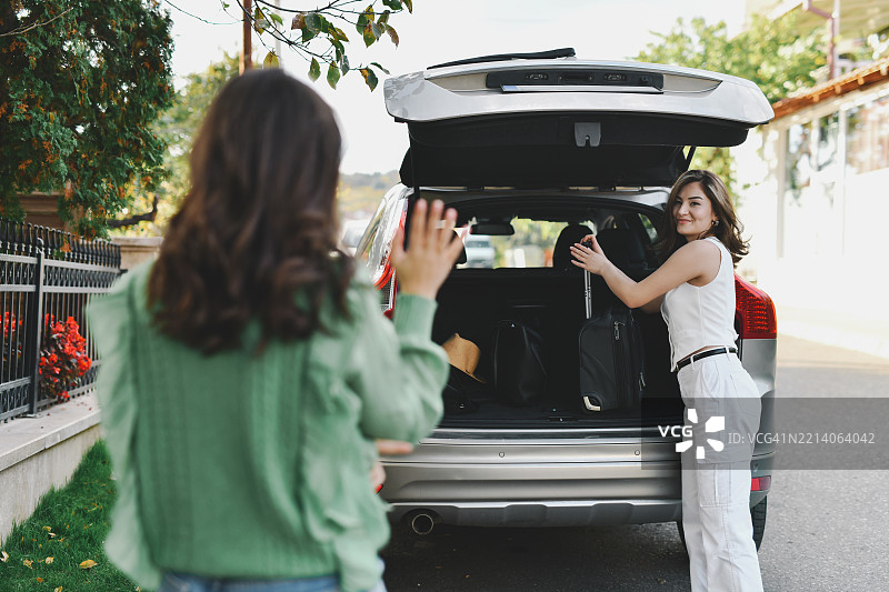 快乐的姐妹们在夏季假期前打包汽车后备箱并挥手告别图片素材