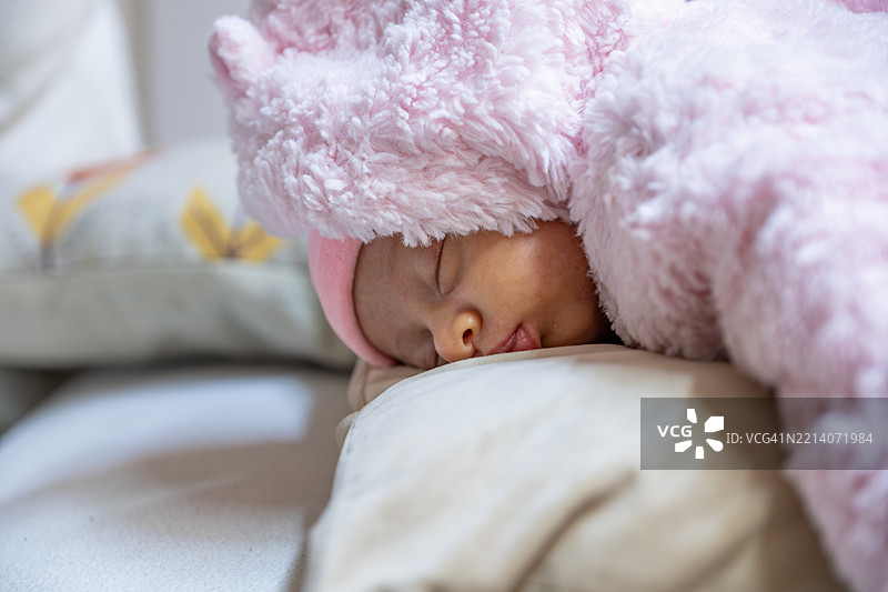 穿着舒适粉色服装的婴儿安静地躺在柔软的枕头上睡觉图片素材