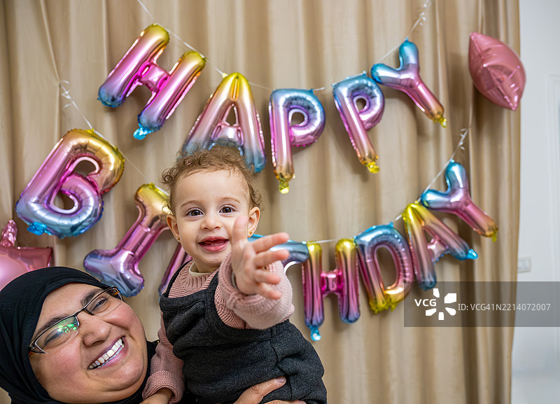 母亲在五彩气球前与孩子庆祝生日图片素材