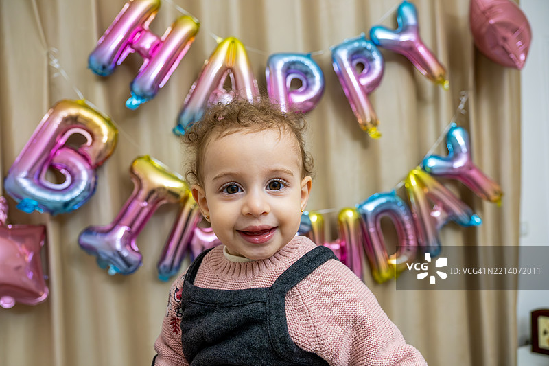 微笑的孩子在生日派对上庆祝，周围有五彩缤纷的气球装饰图片素材