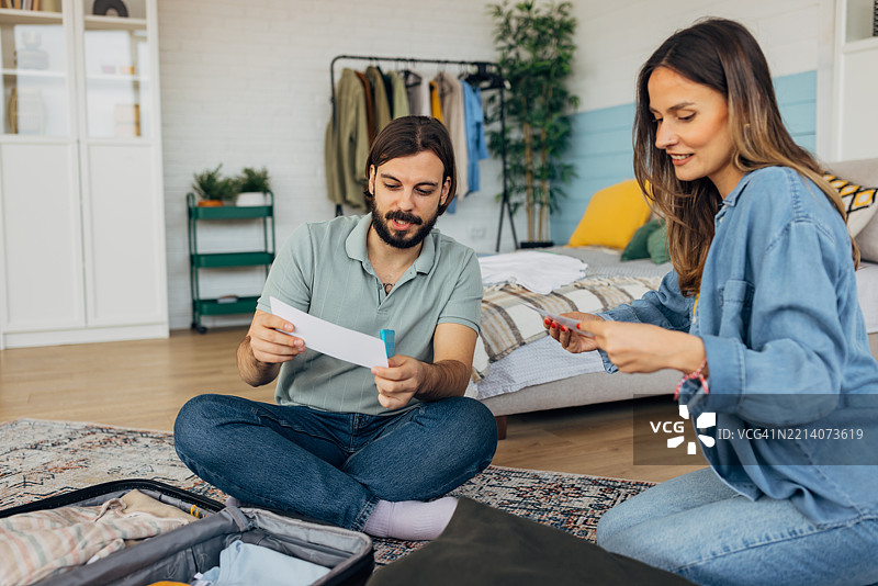 一对恩爱情侣正在收拾行李箱，准备飞机票，准备出行。图片素材