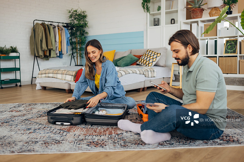 恩爱情侣在卧室为夏季旅行打包行李箱图片素材