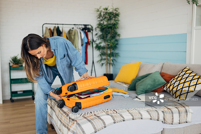 女人合上装满衣物的行李箱，准备出发旅行。图片素材