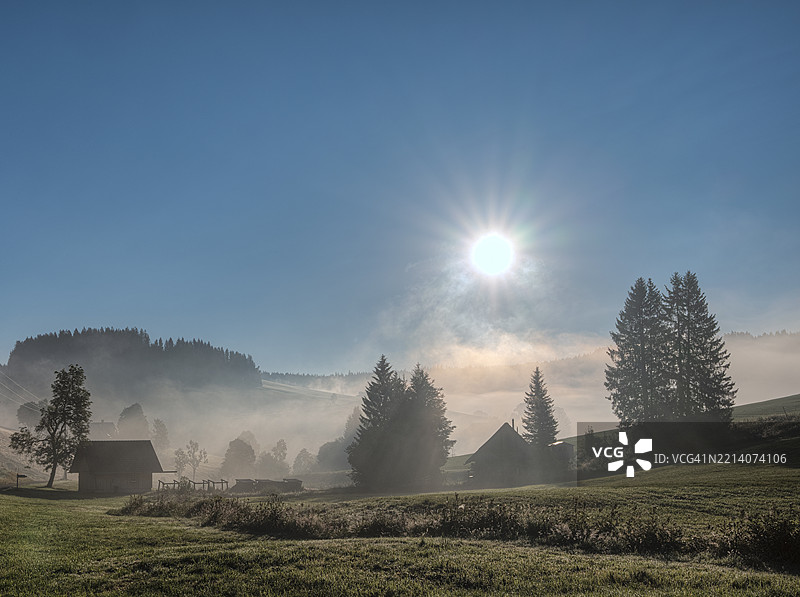 上黑森林的雾霭日出:日出时,雾气散去,冷杉树和面包店小屋显现。约斯塔尔的侧谷。蒂蒂湖 - 新城。上黑森林,黑森林,巴登-符腾堡,德国,欧洲图片素材