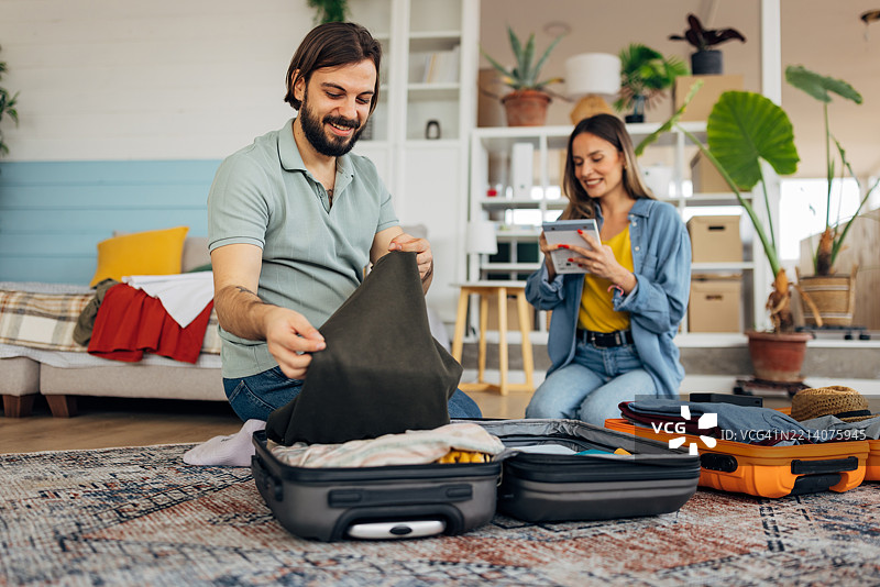 无忧无虑的男女在旅行前享受准备，打包行李箱并决定带什么衣物去旅行图片素材