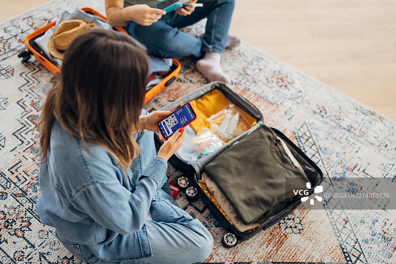 一位女性在手机上查看她的电子飞机票，手机屏幕上显示着一个条形码。图片素材