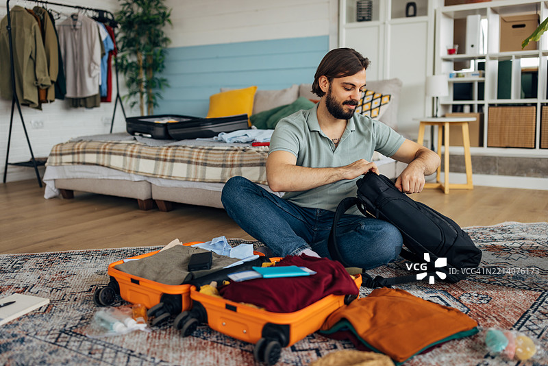 帅气的男人在卧室里收拾行李，准备出行图片素材