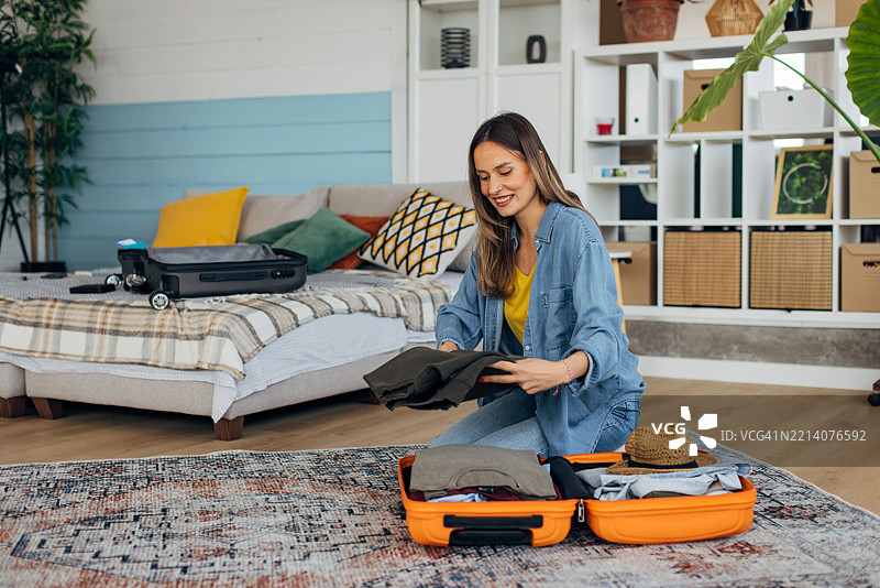 美丽的女性正在准备旅行，整齐地打包行李箱里的衣物和配饰。图片素材