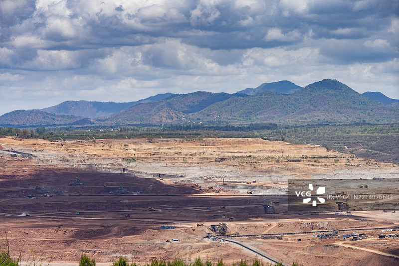 大型露天矿场的鸟瞰图，展示了输送带和工业机器正在挖掘土壤和矿物。图片素材