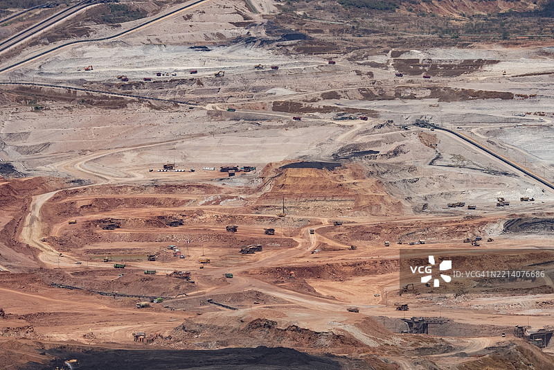 大型露天矿场的鸟瞰图，展示了输送带和工业机器正在开采土壤和矿物。图片素材